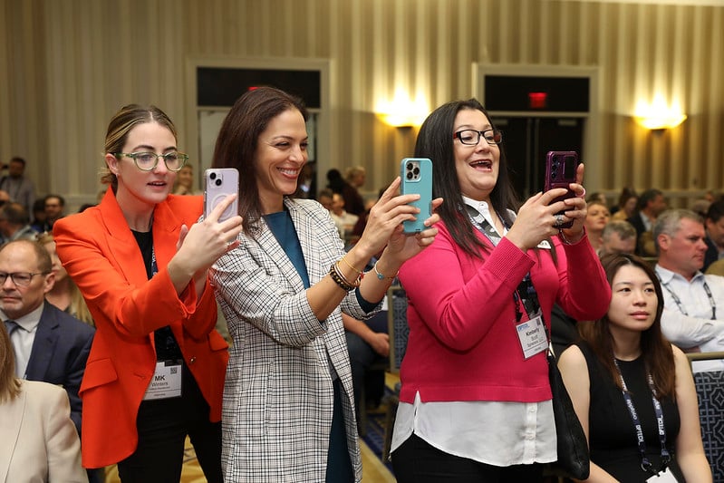 Attendees holding phones taking pictures