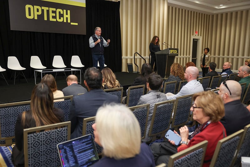 Attendees listening to speaker on OPTECH stage